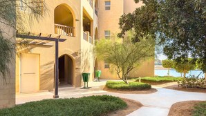 Un immeuble doté de nombreux balcons, d’une entrée abritée et d’une cour aménagée avec des allées et de la verdure.