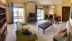 A living room with a sofa, a coffee table, a TV, and a fireplace. - Pond and Pines - Seaside apartments - 1st floor (Epanomi)