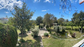 A garden with a variety of trees and shrubs, a stone pathway, and a small pond. - Pond and Pines - Seaside apartments - 1st floor (Epanomi)