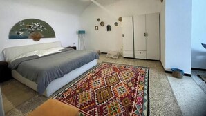 Une chambre à coucher comprenant un lit, un tapis à motifs, un luminaire suspendu, une armoire et un élément décoratif mural.