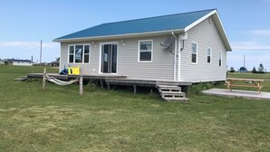 A small, single-story house with a blue roof, a front porch, and a satellite dish. - Darnley, PEI Cottage : Plan a September Getaway Today! (Kensington)