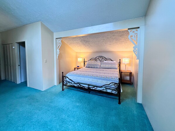 A bedroom with a bed, two bedside tables with lamps, a door, and a carpeted floor. - Spacious Condo at Sugar Mountain- Golf Course View (Sugar Mountain)