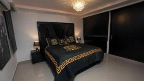 A bedroom with a large bed, a chandelier, and a sliding door closet. - Boss-Level Hideout! (edificio calamary)