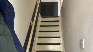 A staircase with white steps and black risers, leading to a landing. - Charming House Luton Airport (Luton)