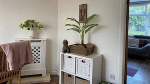 A room with a white console table, a potted plant, a small statue, and a painting on the wall. - Charming House Luton Airport (Luton)