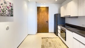 Une cuisine moderne avec des meubles blancs, un réfrigérateur en acier inoxydable et une porte en bois.