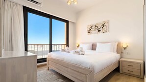 A bedroom with a large bed, bedside tables, a nightstand, a window with a view, and a ceiling light fixture. - Xuru Stays I Cool & Curated 1bdr @ Kamaran El Gouna (El Gouna)
