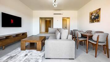 A modern living room with a sectional sofa, wooden coffee table, and dining area with chairs and a table.