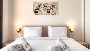 A hotel room with a neatly made bed, two pillows, two wall-mounted lamps, and a painting above the bed. - Xuru Stays I Cool & Curated 1bdr @ Kamaran El Gouna (El Gouna)