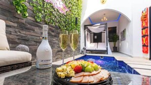 A dining table with a bottle of wine, glasses, and a fruit platter.