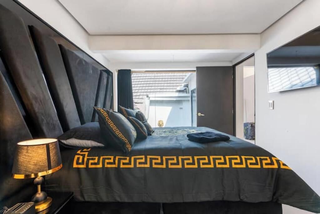 Una camera da letto moderna con un letto, un comodino e una lampada.