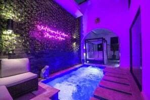 A spa area with a hot tub, seating, and a wall with a neon sign.