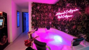 Ein modernes Badezimmer mit einer großen Badewanne, einer Neonreklame und einer Wanddekoration.