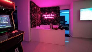 Ein Empfangsbereich mit einer Neonreklame, einem Empfangstresen und einem Bildschirm, der ein Spiel zeigt.