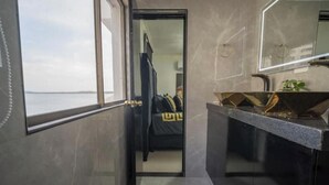 A modern bathroom with a large mirror, a black sink, and a view of a room with a bed and a window. - Serenity Escape (CARTAGENA BOLIVAR)