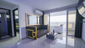 A modern living room with a sofa, a coffee table, and a large mirror. There is a sliding glass door leading to a balcony. - Serenity Escape (CARTAGENA BOLIVAR)