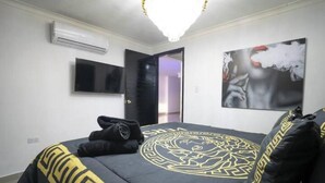 A bedroom with a bed, a television, an air conditioning unit, and a door leading to another room. - Serenity Escape (CARTAGENA BOLIVAR)