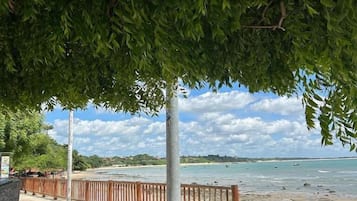 Vista de una playa con una valla de madera y un árbol que da sombra.