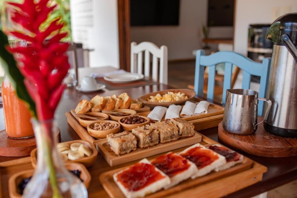A breakfast buffet with various pastries, fruits, and a coffee pot on a wooden table.