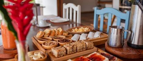A breakfast buffet with various pastries, fruits, and a coffee pot on a wooden table.