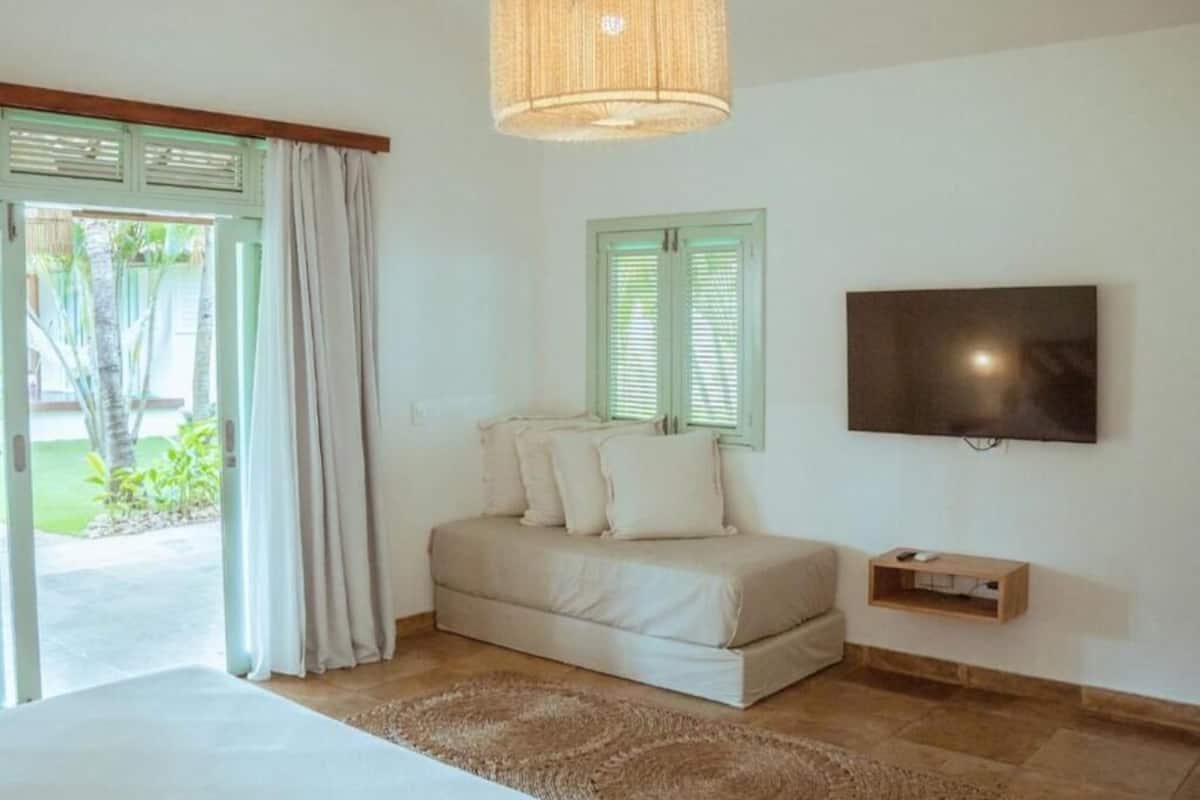 A bedroom with a bed, a TV, and a window with shutters.
