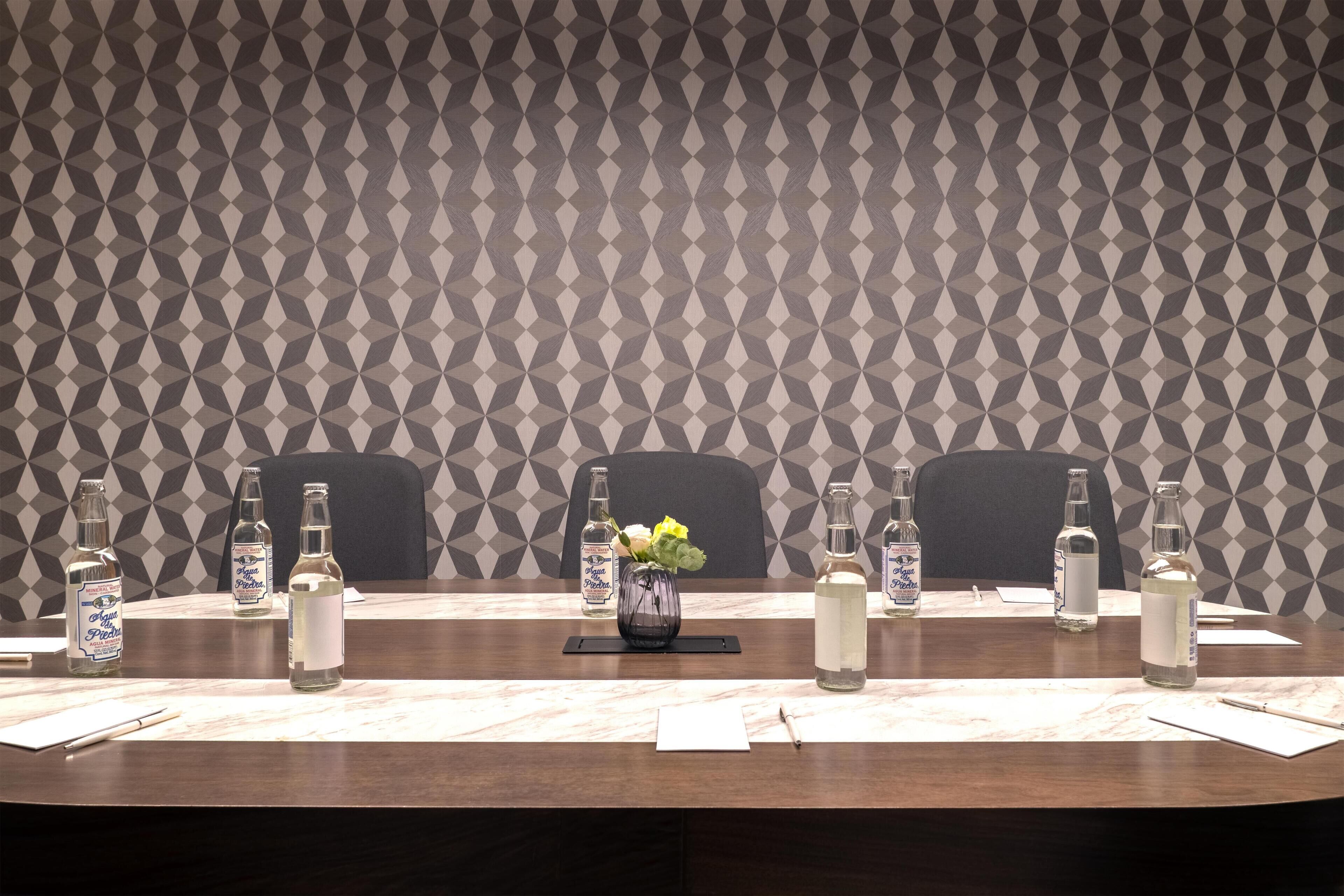 Una mesa de conferencias con botellas de agua, un florero con flores y blocs de notas.