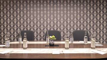 Una mesa de conferencias con botellas de agua, un florero con flores y blocs de notas.
