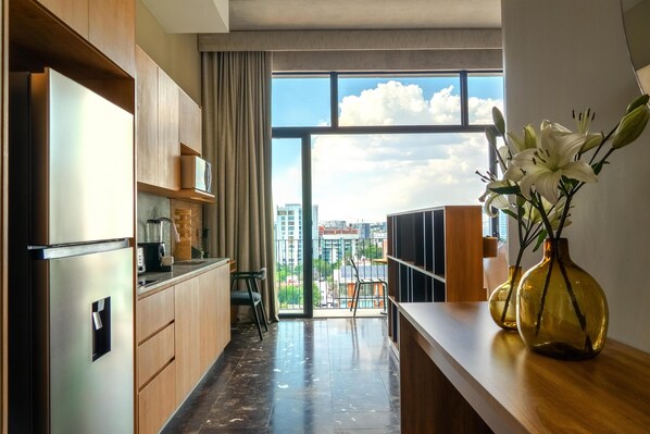 A modern kitchen with a large window, a refrigerator, and a vase with flowers on the counter. - NH Guadalajara Studios (Guadalajara)