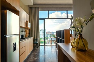 A modern kitchen with a large window, a refrigerator, and a vase with flowers on the counter.