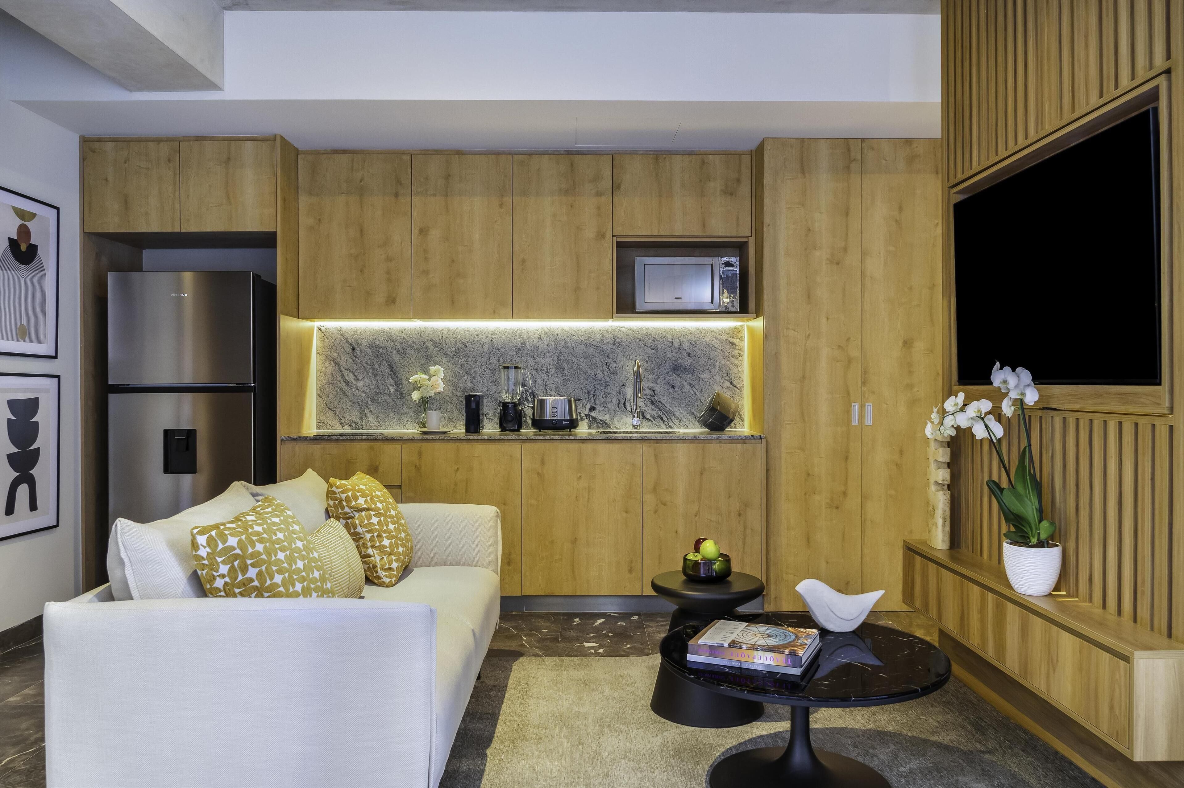 A modern kitchen with wooden cabinetry, a built-in microwave, and a marble countertop.