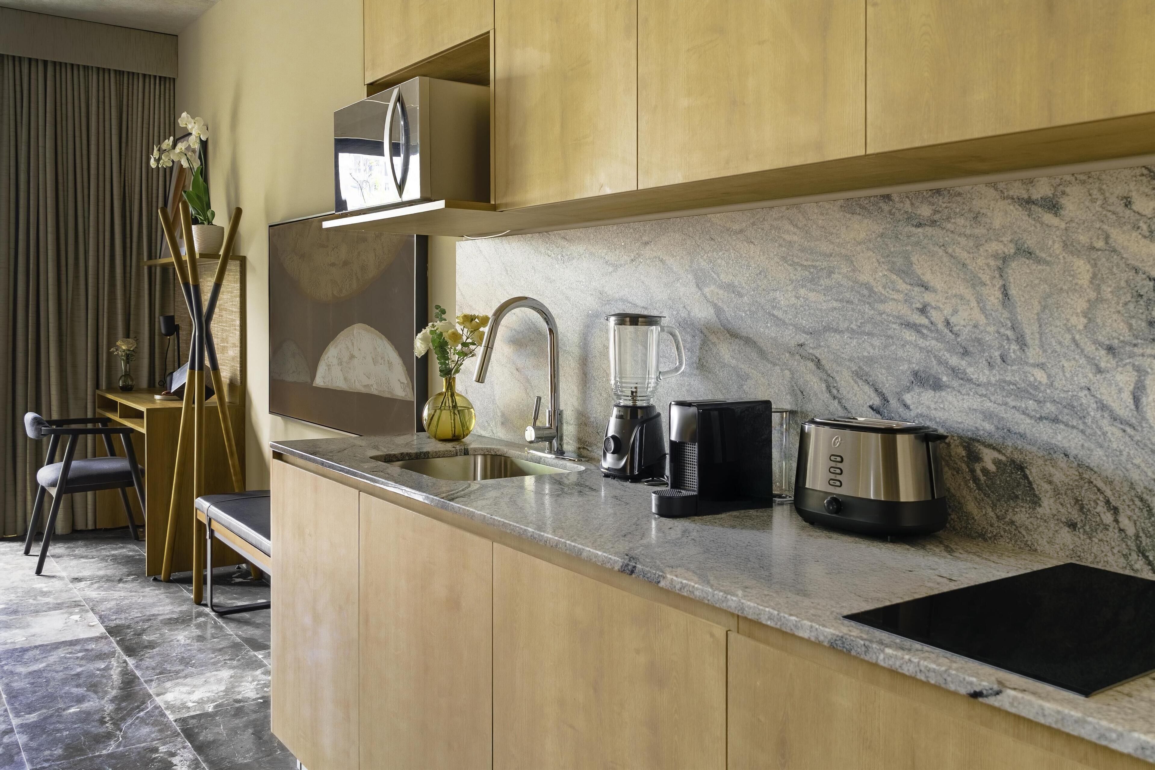 A modern kitchen with a marble countertop, stainless steel appliances, and a wooden dining area.
