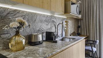 Una cocina moderna con encimera de mármol, un tostador, una tetera y un jarrón con flores.