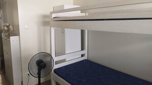 A bunk bed with a fan in a room with white walls and a small table with flowers. - Studio Unit Around Recto U-belt (Manila)