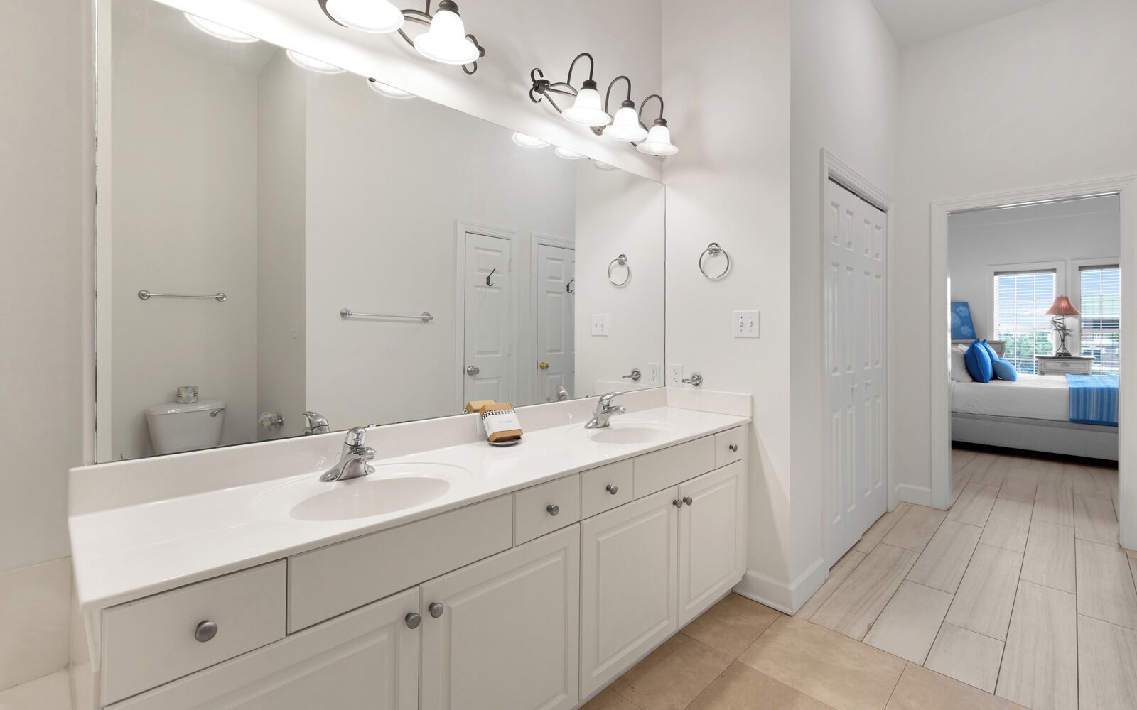 A modern bathroom with a large mirror, two sinks, and a vanity with drawers.