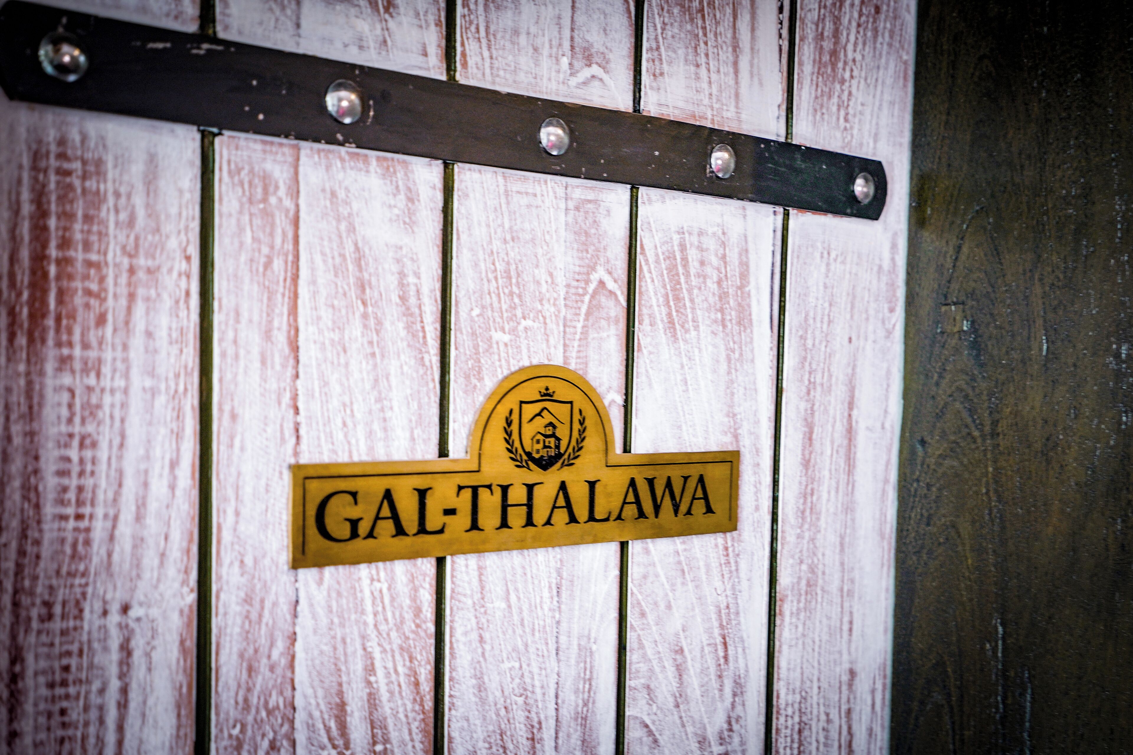 Un letrero de madera con el texto "GAL-THALAWA" y un escudo.
