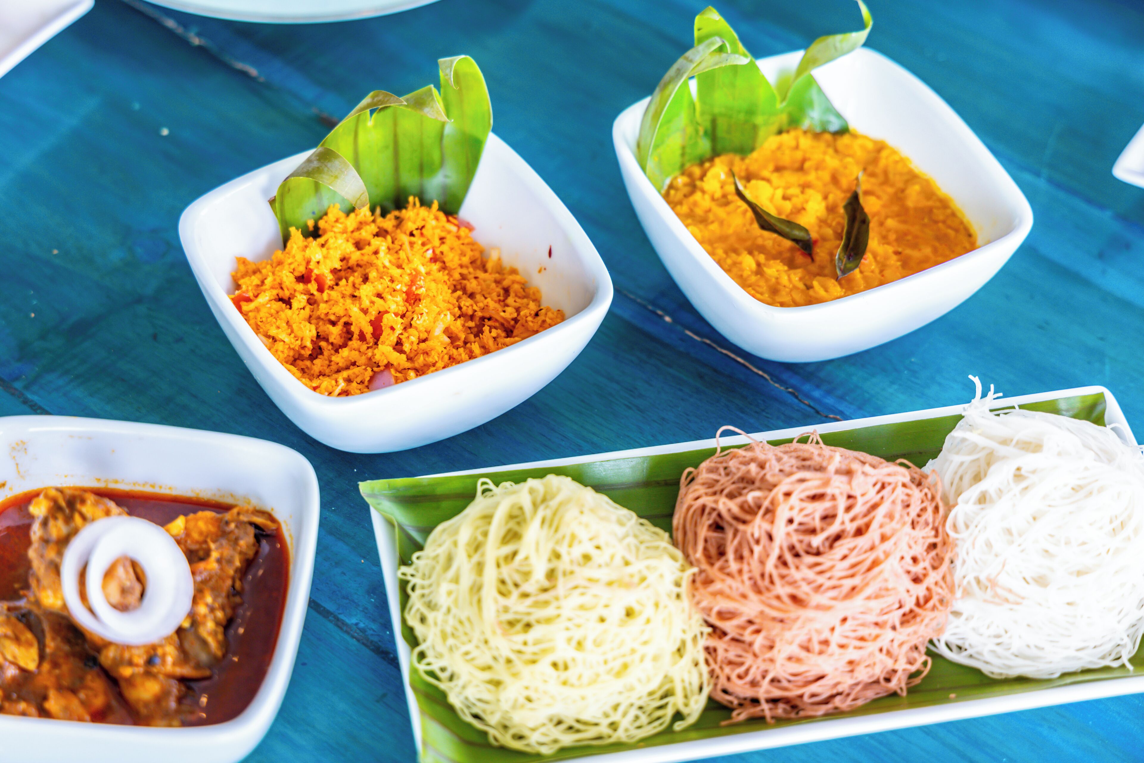 A table with various dishes including rice, noodles, and a curry dish.