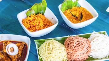 A table with various dishes including rice, noodles, and a curry dish.