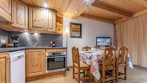 Une cuisine dotée de meubles en bois, d’un lave-vaisselle, d’un four et d’un coin repas avec une table mise pour quatre personnes.