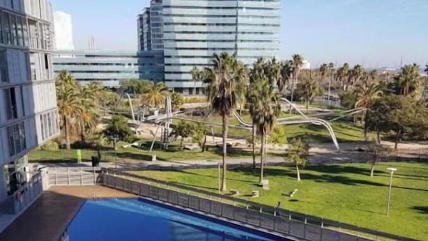 A swimming pool with a view of modern buildings and palm trees.