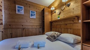 Een houten kamer met een bed, twee handdoeken en een nachtkastje.