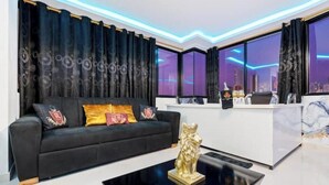 A modern hotel lobby with a black sofa, decorative pillows, a gold statue, and a reception desk.