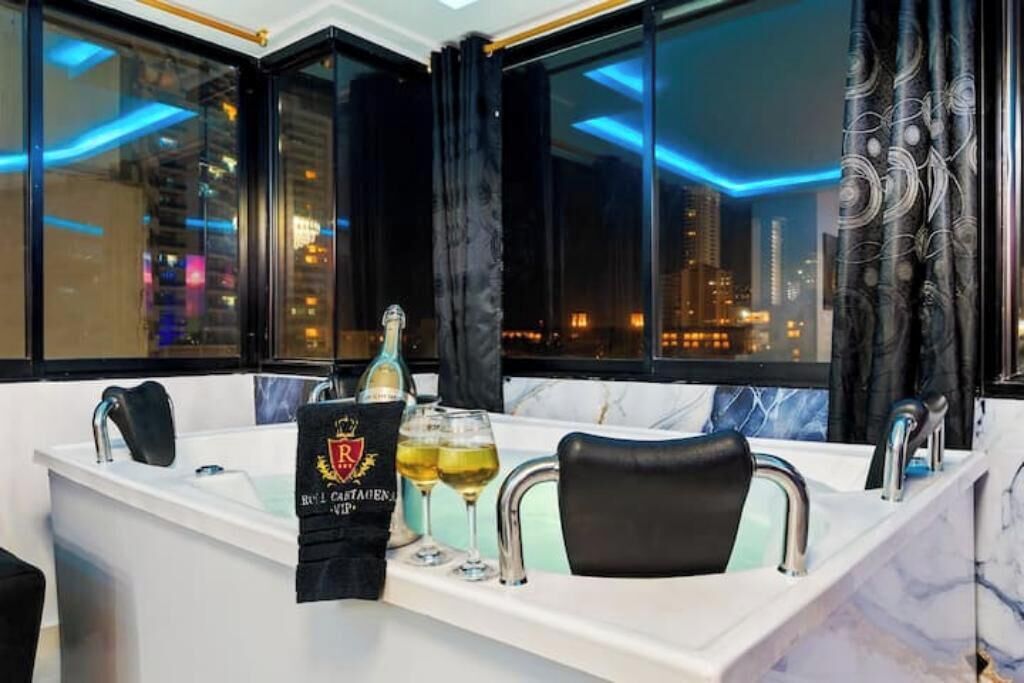 A modern bathroom with a bathtub, two wine glasses, and a bottle of champagne.