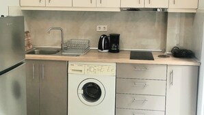 A compact kitchen with stainless steel appliances, a built-in washing machine, and a coffee maker.