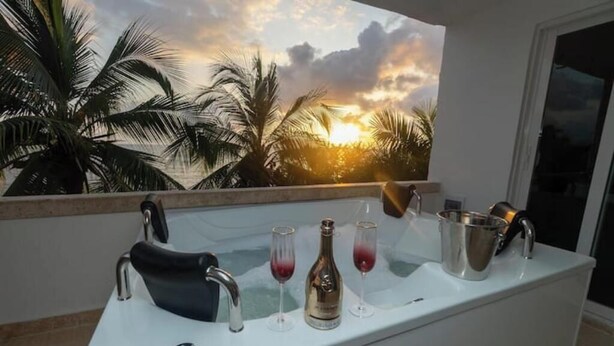 A bar area with a white countertop, a black faucet, and a wine bottle. - Tropical One-Bed Oasis (CARTAGENA BOLIVAR)