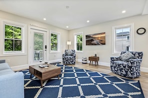 A living room with a blue patterned rug, two patterned armchairs, a wooden coffee table, and a painting on the wall. - Bourne By The Beach – Beautiful Home for 6 Near Shops and the Shore (Wells)