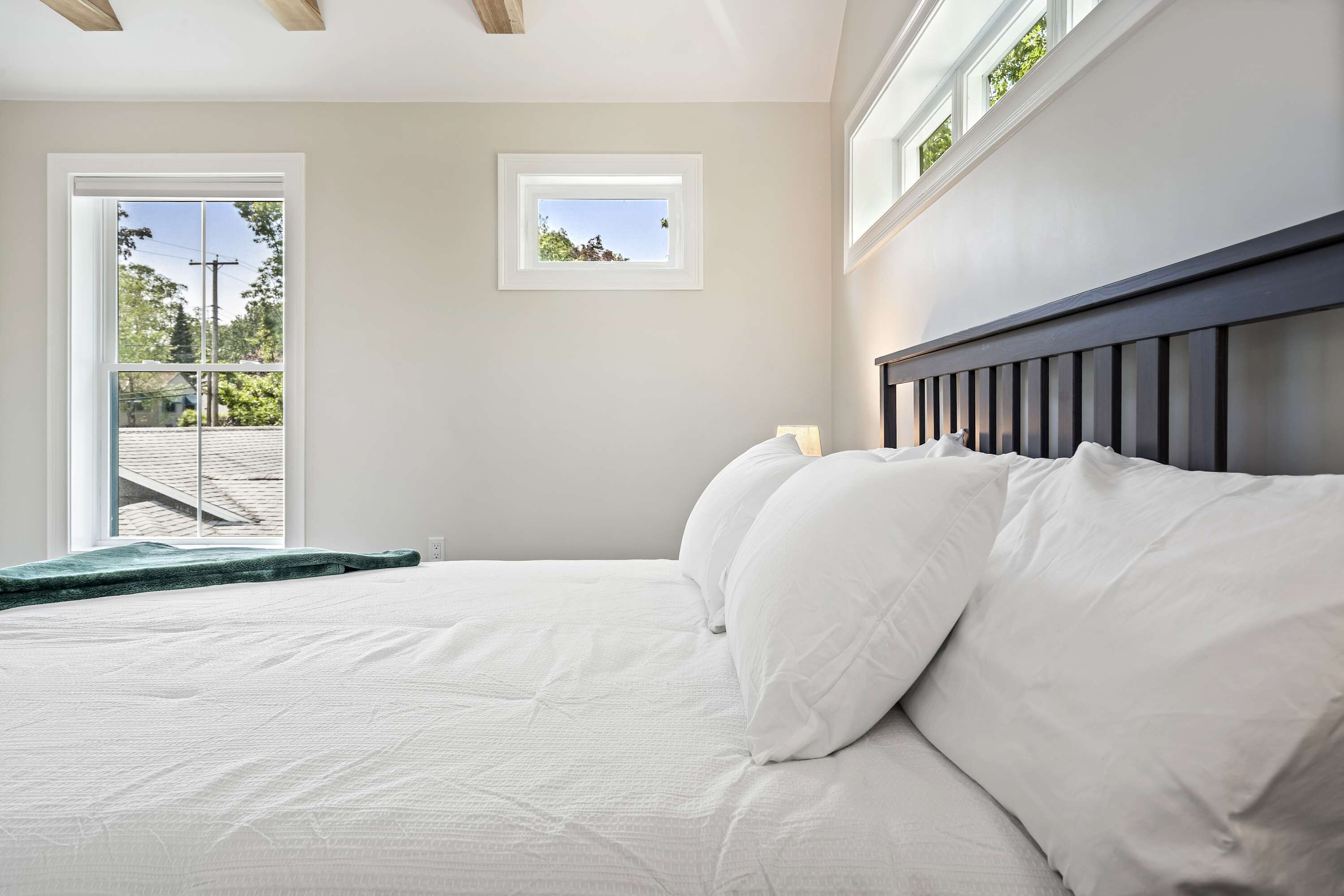 A bedroom with a bed, a window, and a view of the outdoors.