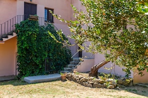 Un edificio con una scala, un muro in pietra e un albero sullo sfondo.