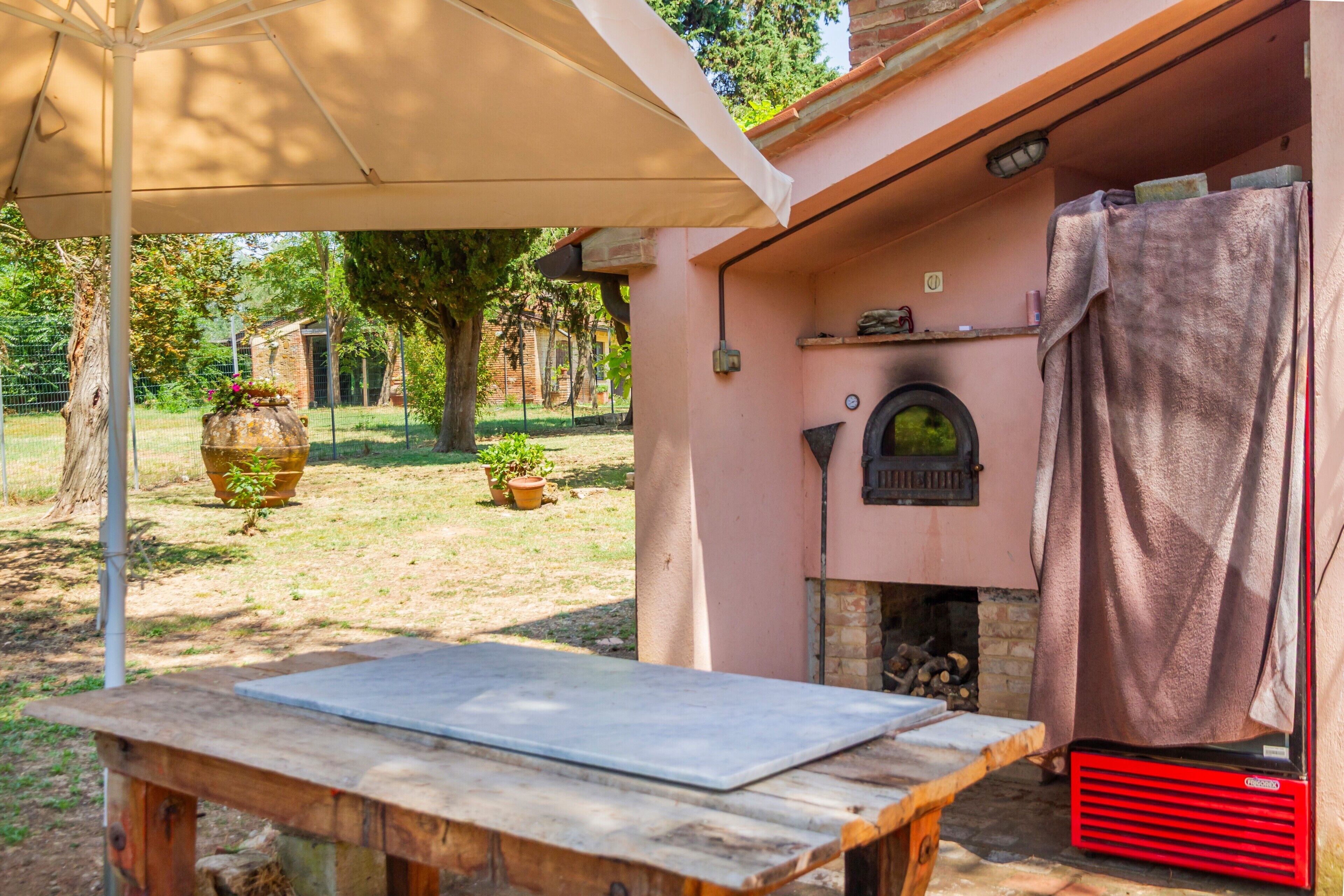 A rustic outdoor seating area with a table, a brick fireplace, and a covered space.