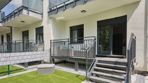 A modern building with balconies, a small garden area, and a staircase leading to the entrance. - 11 listopada 70 c (Świnoujście)