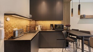 A modern kitchen with dark cabinets, a built-in microwave, and a dining area with a wooden table and chairs. - 11 listopada 70 c (Świnoujście)